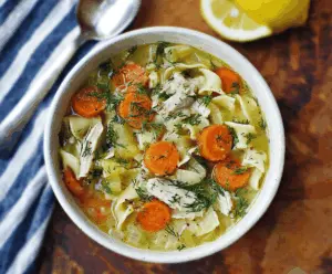 Hearty Lemon Dill Chicken Noodle Soup in a bowl with fresh herbs and lemon slices, perfect for comforting meals