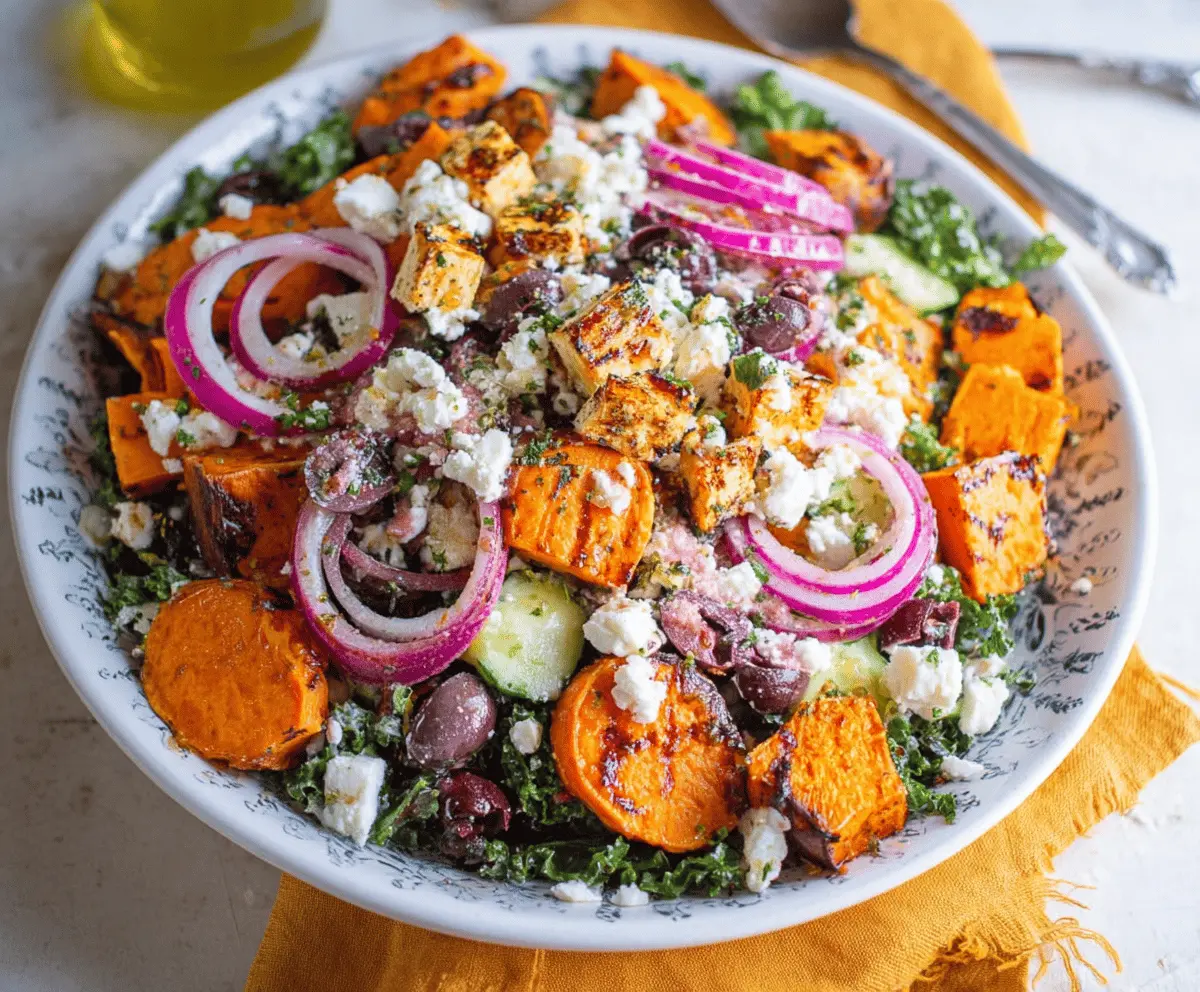 Colorful sweet potato Greek salad with diced sweet potatoes, cucumbers, cherry tomatoes, red onion, Kalamata olives, feta cheese, and fresh herbs in a bowl, perfect for a healthy, flavorful meal.