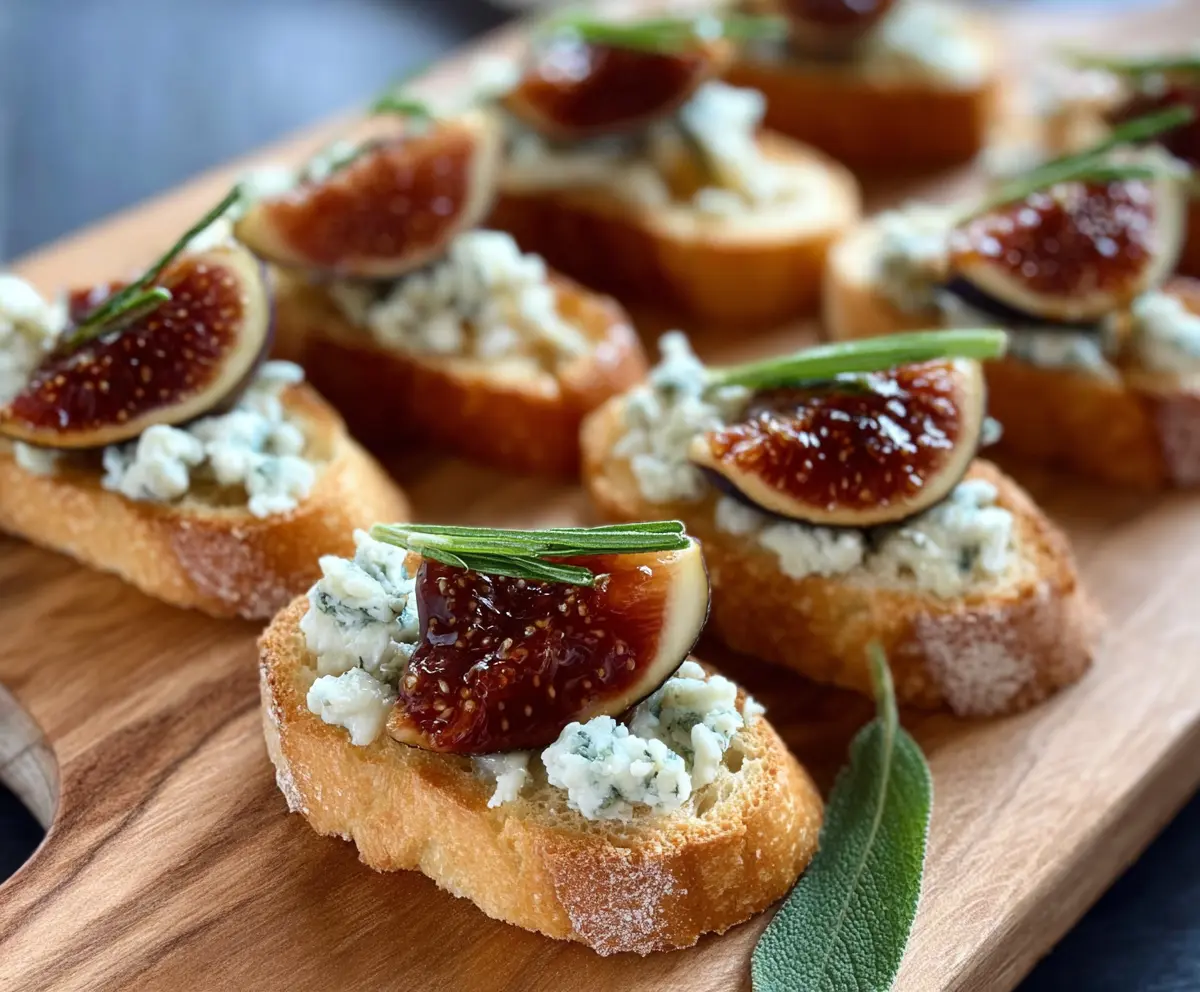 Delicious Fig and Blue Cheese Crostini topped with fresh herbs on a rustic wooden board.