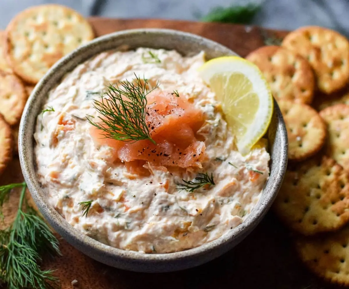 Delicious smoked salmon dip served with fresh herbs and savory crackers.