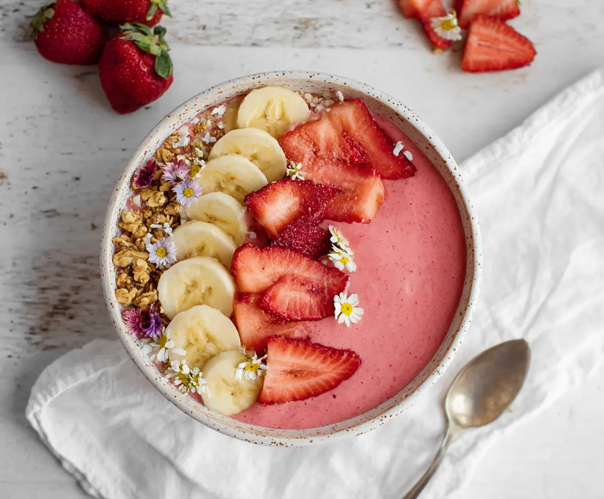 Delicious strawberry banana smoothie bowl topped with fresh fruit and granola