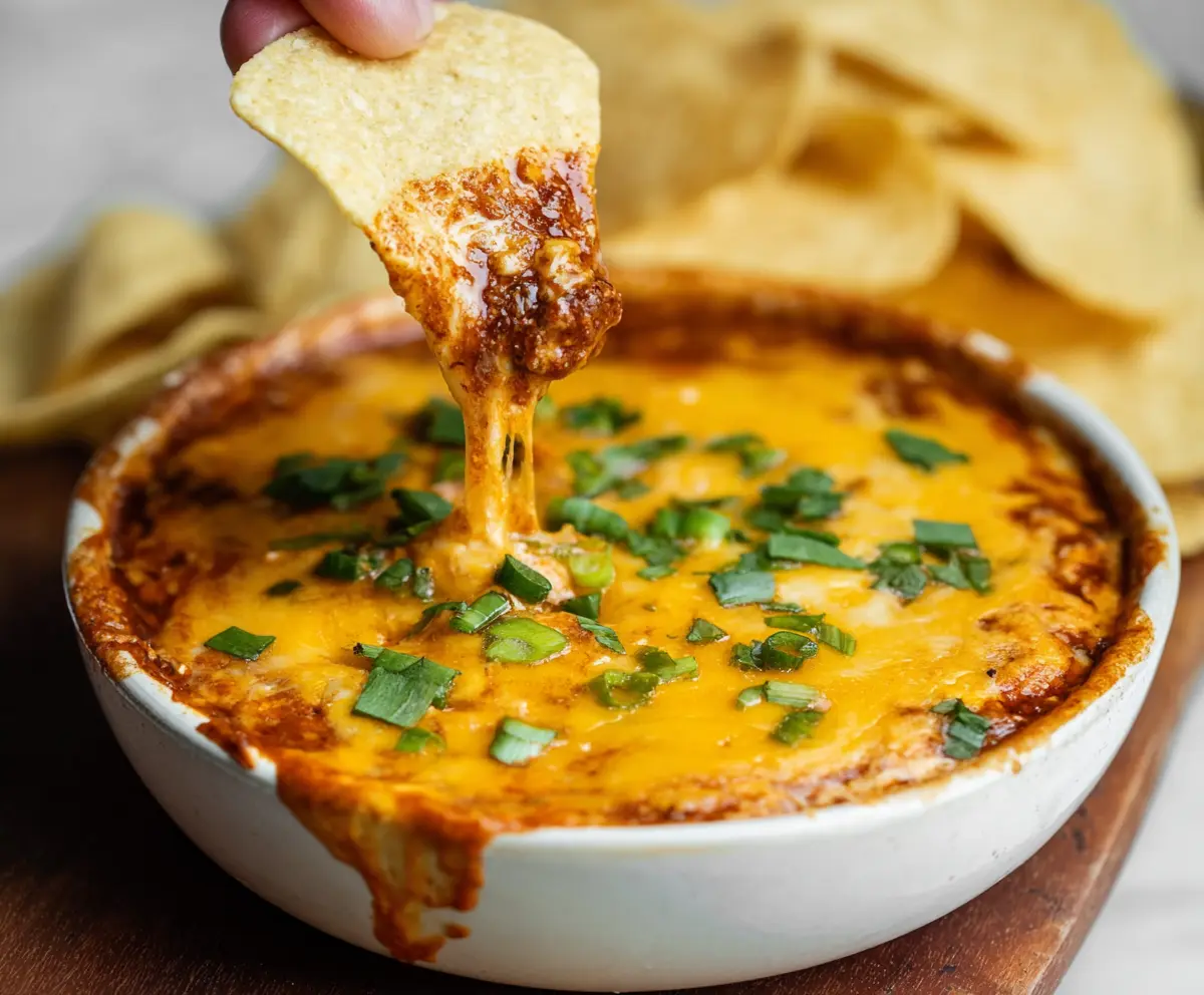 Delicious spicy chili cheese dip served with tortilla chips on a festive table.