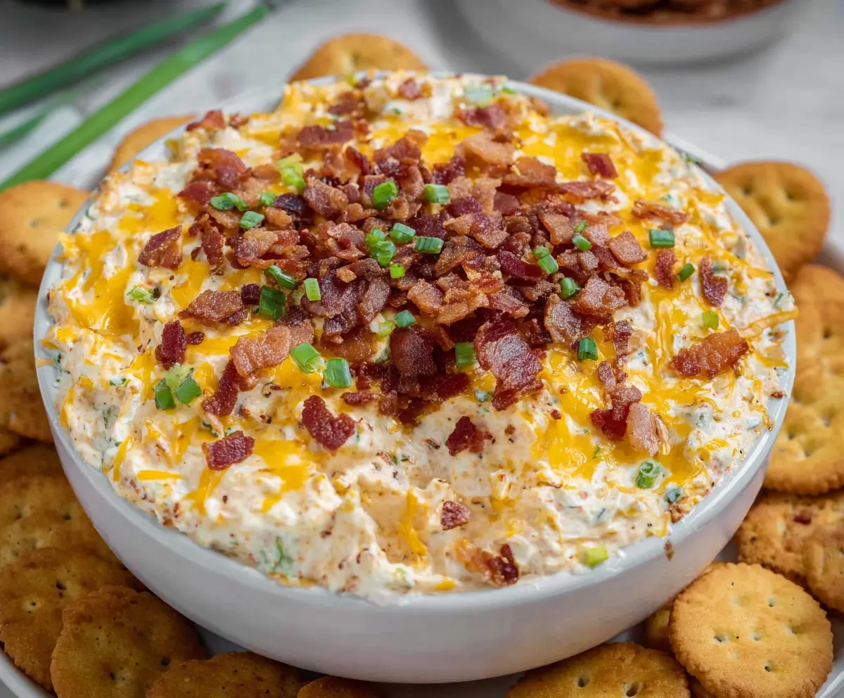 Bacon cheddar crack dip in a bowl with crispy bacon pieces and melted cheese for a delicious appetizer.