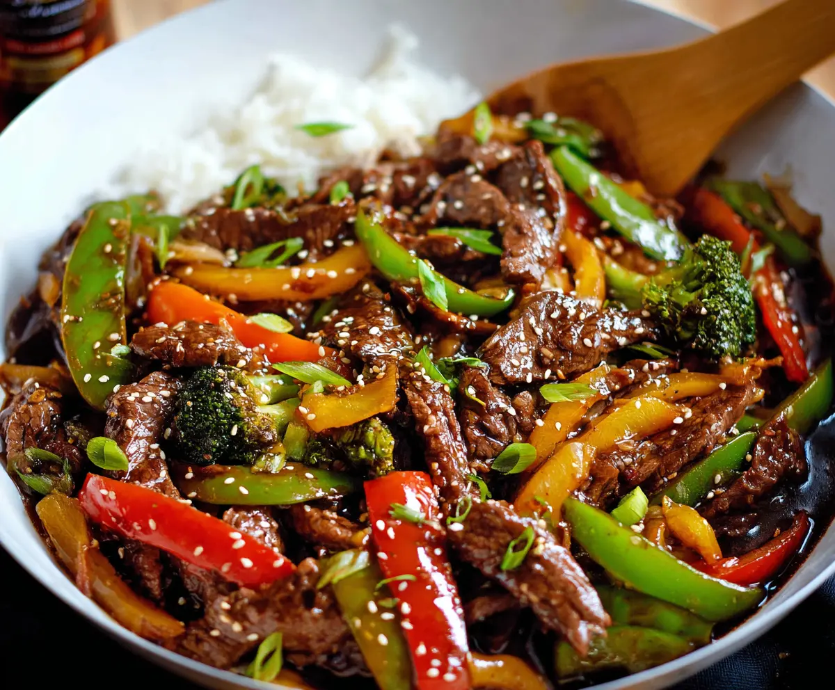 Delicious beef stir fry with colorful vegetables served in a bowl on a wooden table.