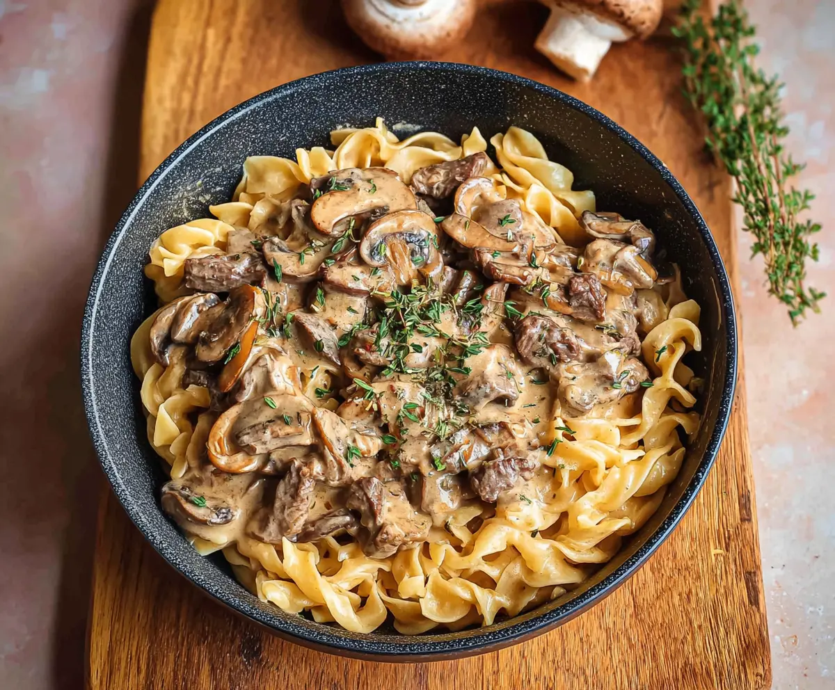 Delicious beef stroganoff served over creamy pasta with mushrooms and herbs