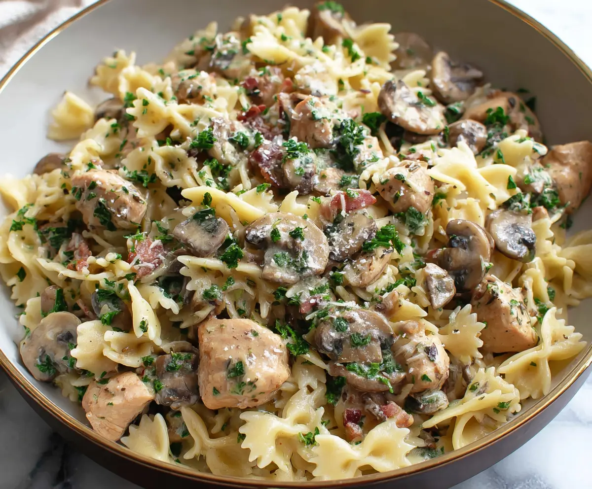 Delicious chicken and mushroom pasta served in a bowl, topped with herbs.