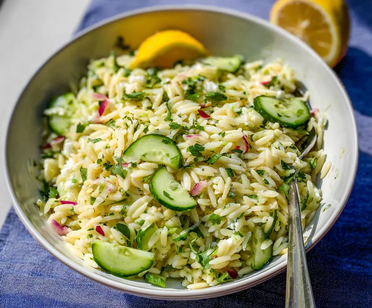 Fresh cucumber lemon orzo salad on a white plate, garnished with herbs for a light, healthy meal.