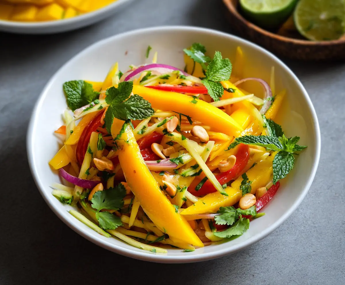 Fresh Thai Mango Salad with herbs, chili, and lime, served in a rustic bowl.