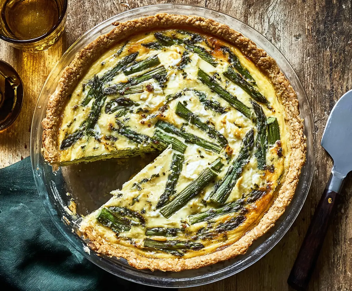 Delicious asparagus and Gruyere cheese quiche served on a white plate.