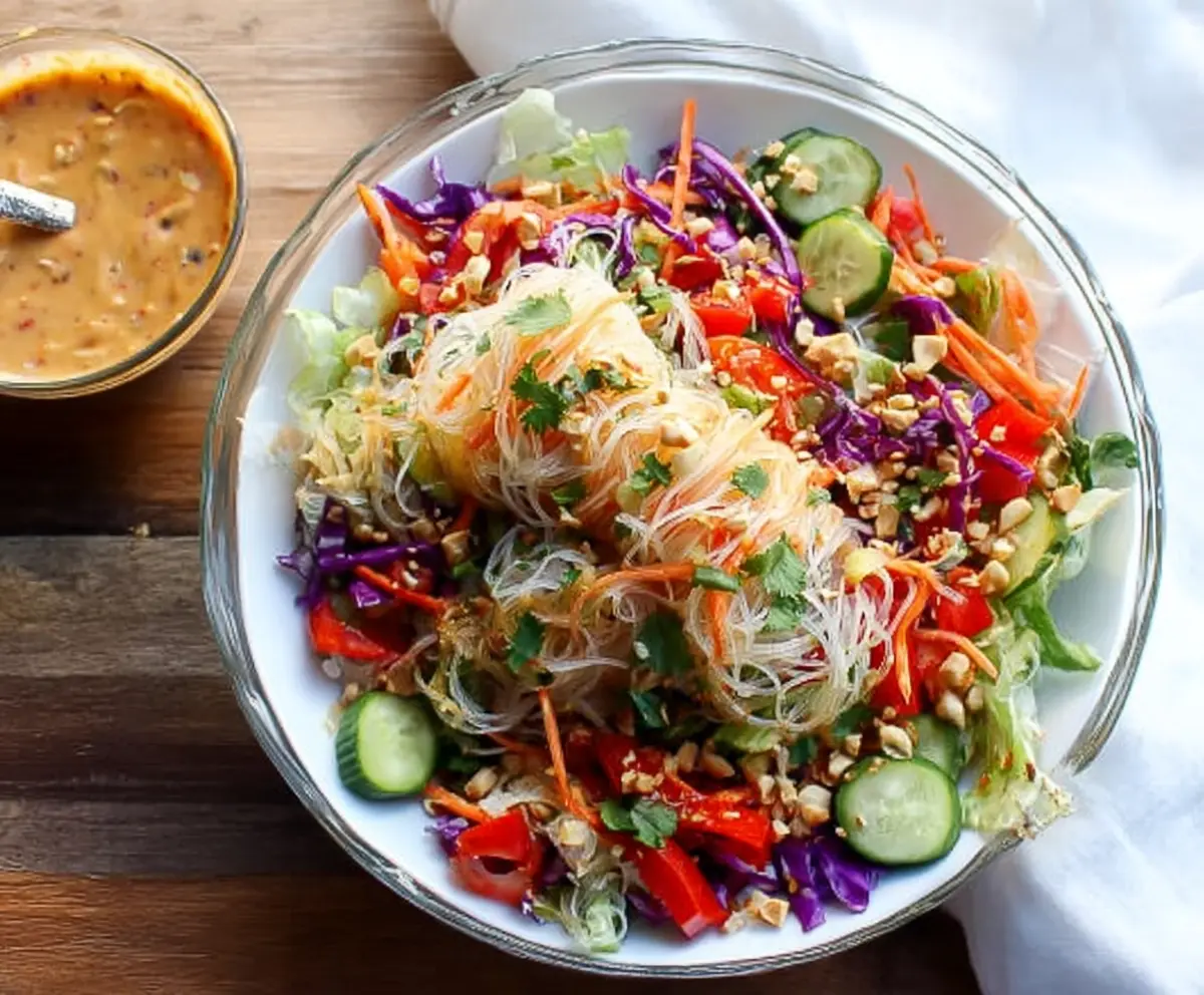 Colorful spring roll salad topped with fresh vegetables and herbs, drizzled with spicy ginger dressing.